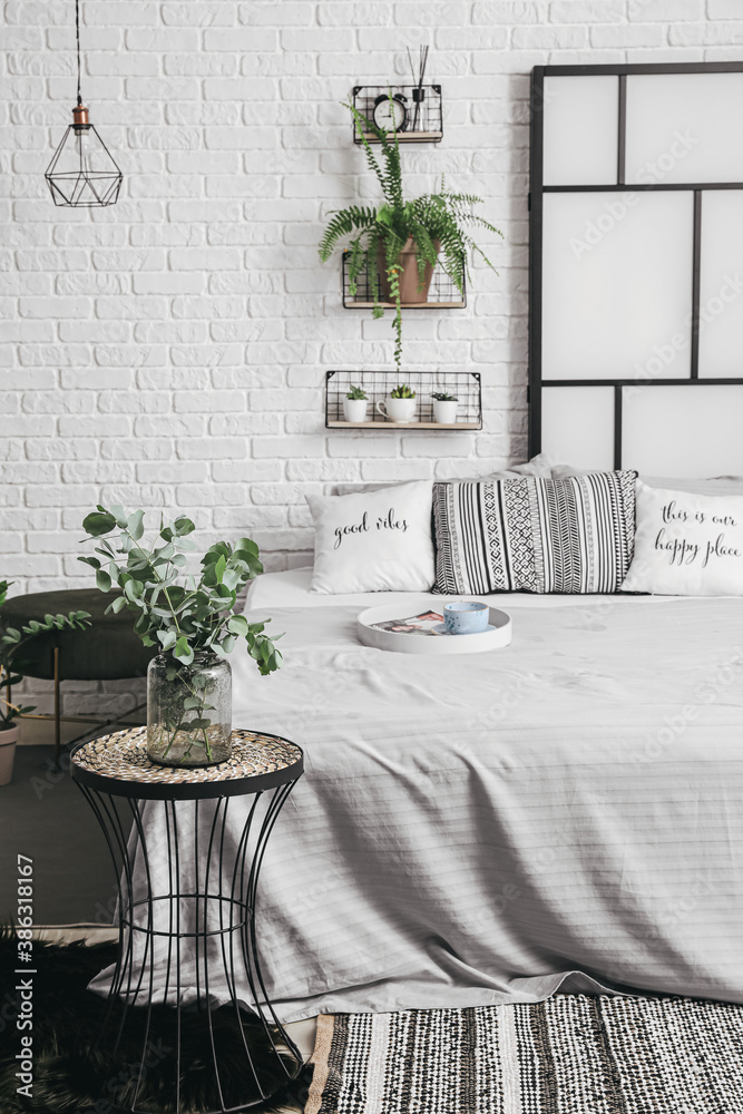 Interior of modern stylish bedroom with shelves and houseplants