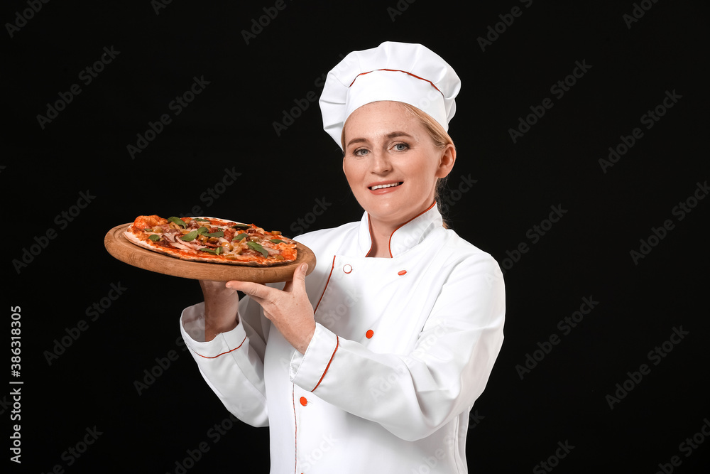 Mature female chef with tasty pizza on dark background