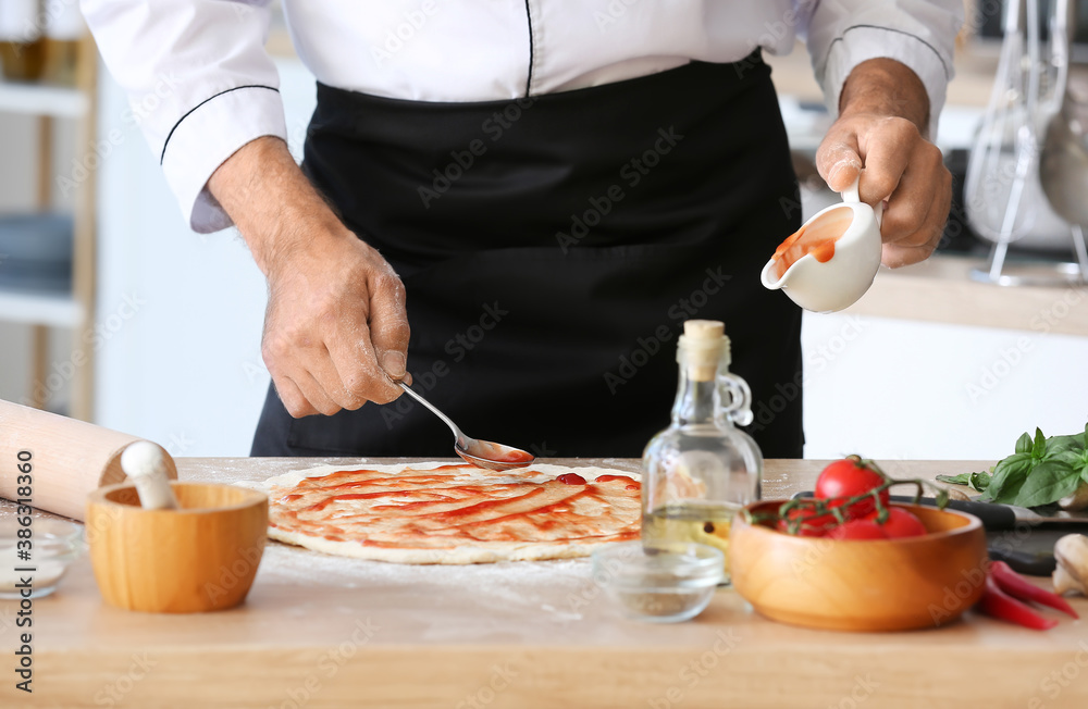 Mature male chef cooking tasty pizza in kitchen, closeup