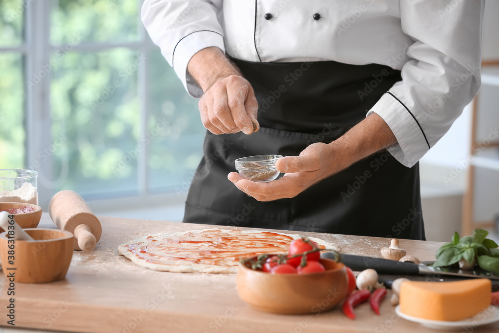 Mature male chef cooking tasty pizza in kitchen, closeup