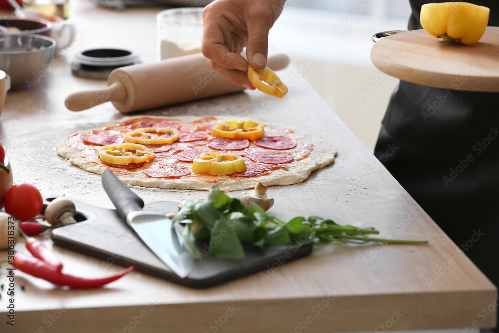 Mature male chef cooking tasty pizza in kitchen, closeup