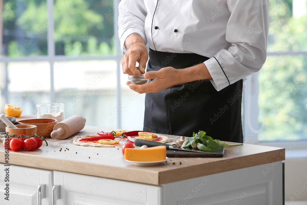 Mature male chef cooking tasty pizza in kitchen