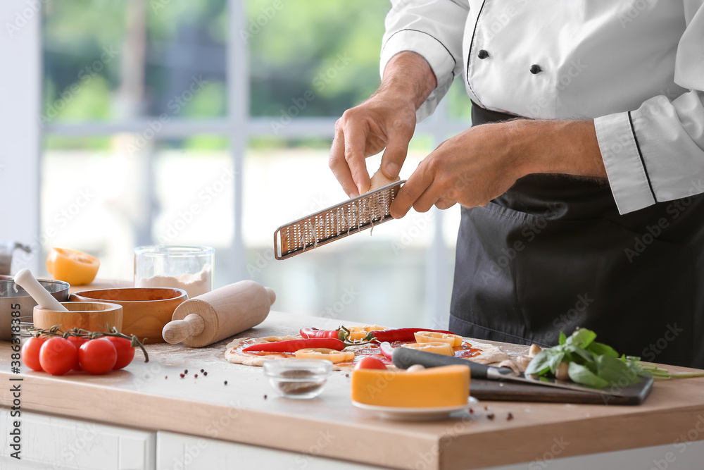 Mature male chef cooking tasty pizza in kitchen