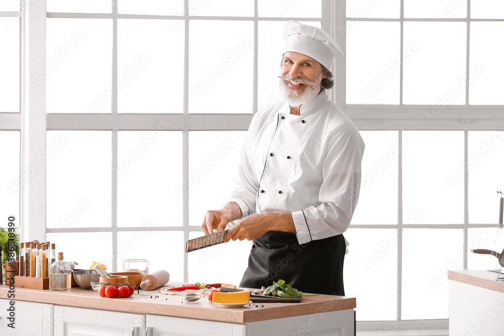 Mature male chef cooking tasty pizza in kitchen