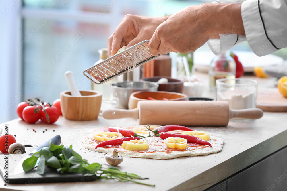 Mature male chef cooking tasty pizza in kitchen, closeup