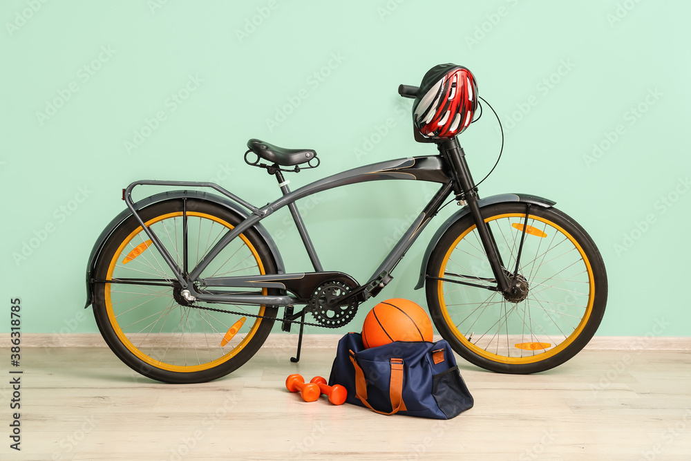 Set of sport equipment with bicycle near color wall