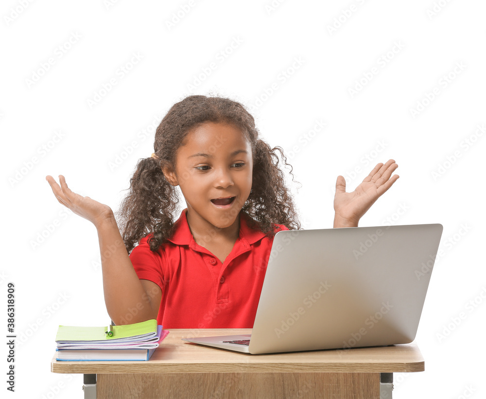 African-American schoolgirl with laptop sitting at school desk against white background