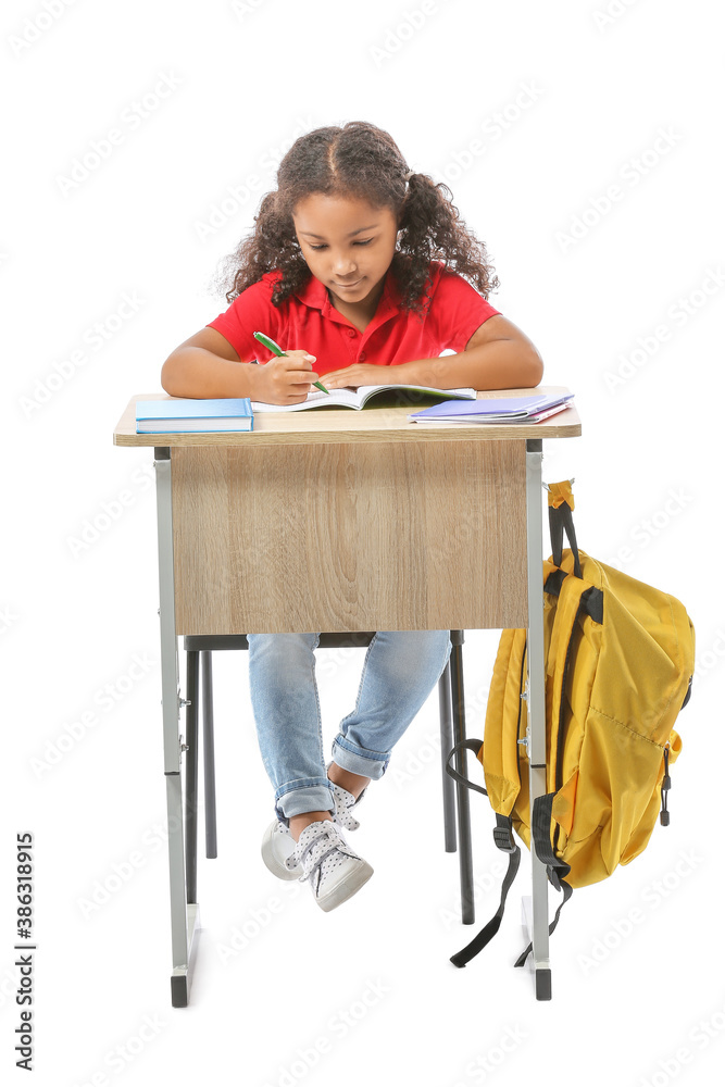 African-American schoolgirl sitting at school desk against white background