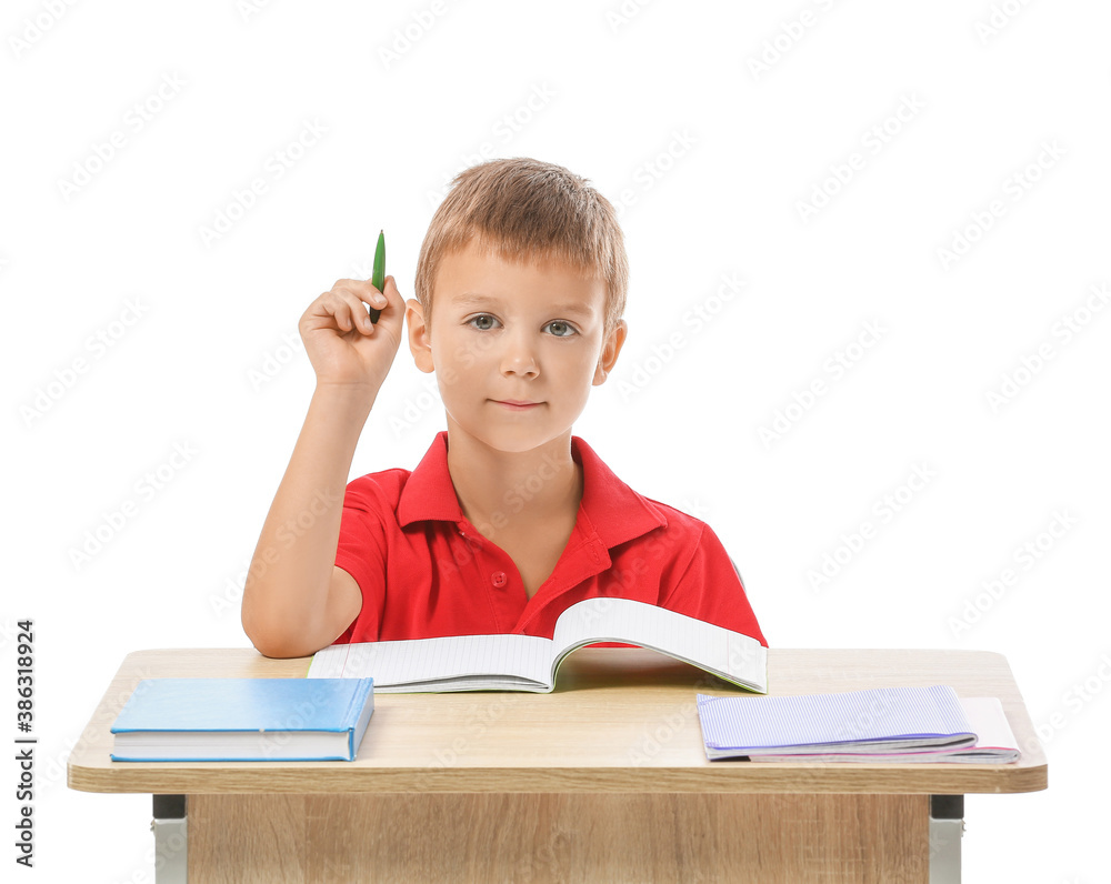 Little pupil sitting at school desk against white background