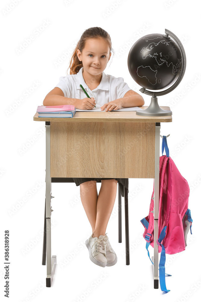 Little pupil sitting at school desk against white background