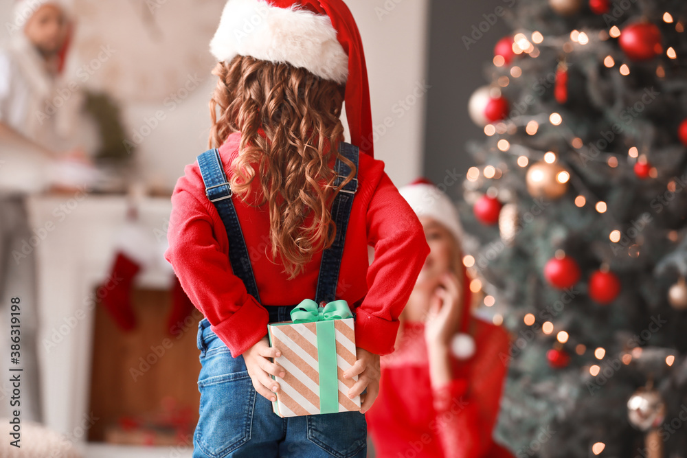 Cute girl hiding gift for her parents on Christmas eve