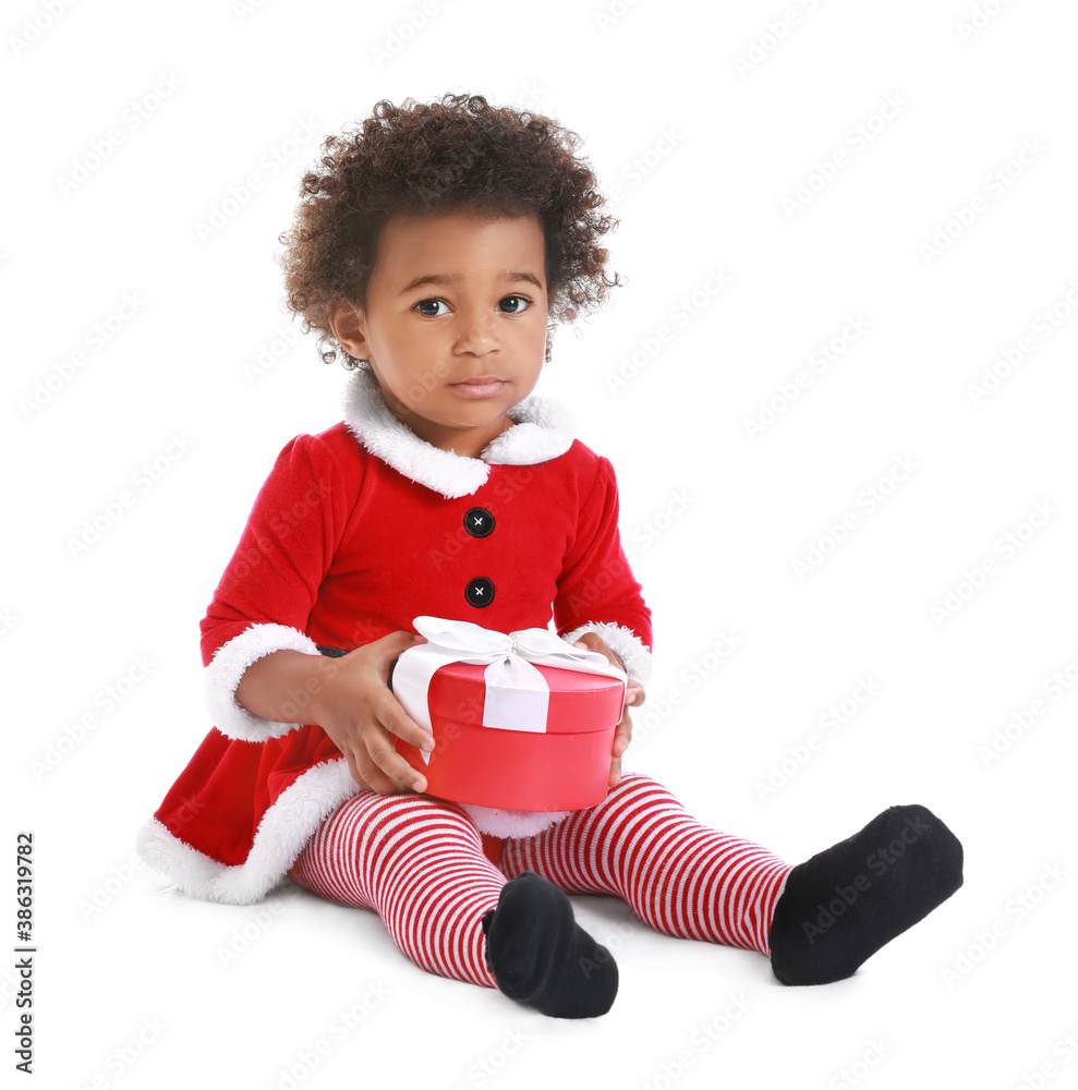 Cute African-American baby girl dressed as Santa and with Christmas gift on white background