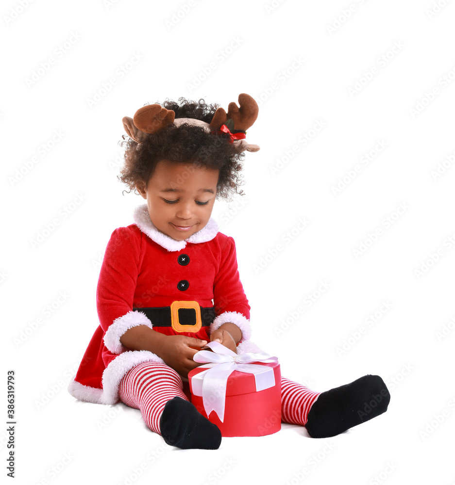 Cute African-American baby girl dressed as Santa and with Christmas gift on white background