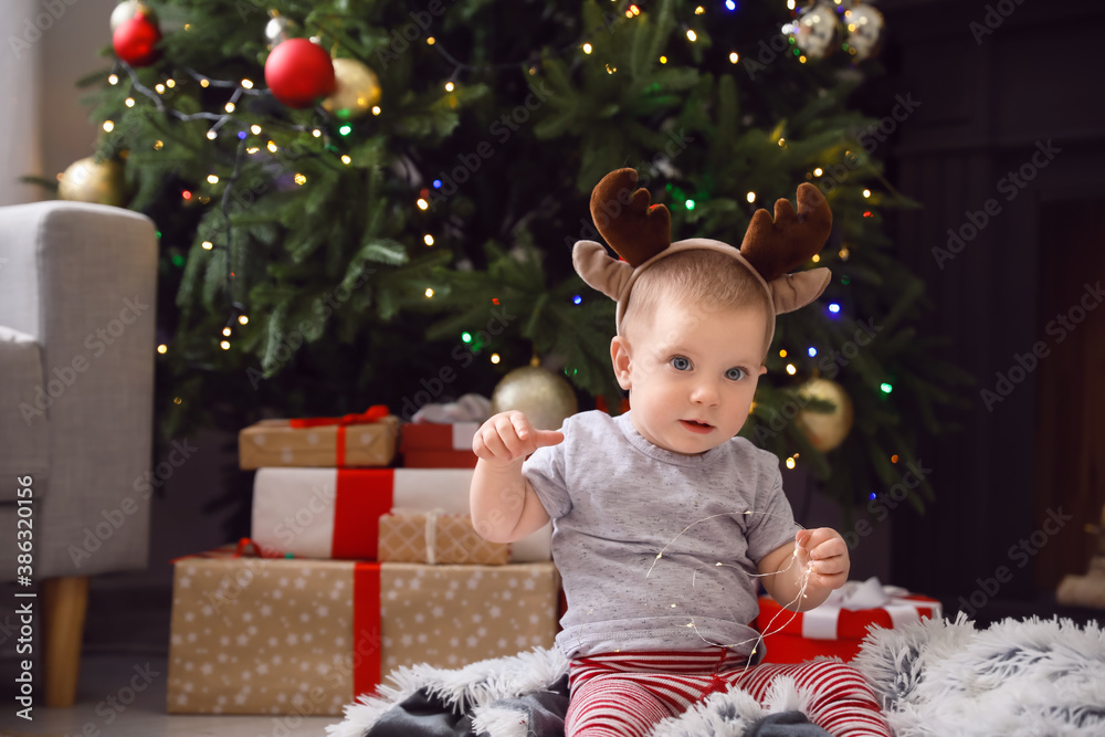 Cute little baby with deer horns at home on Christmas eve