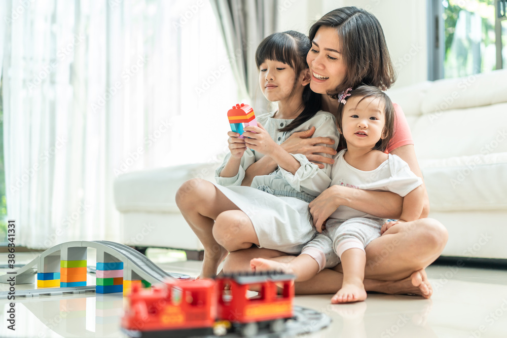 Beautiful mother hugging her children with smiling in the living room.