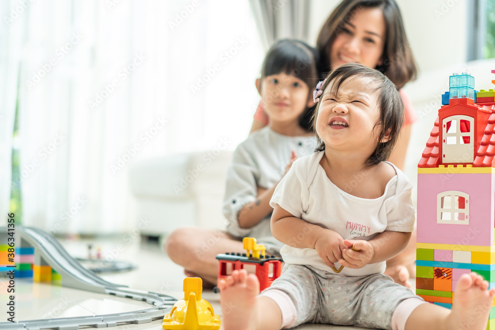 Beautiful mother hugging her children with smiling in the living room.