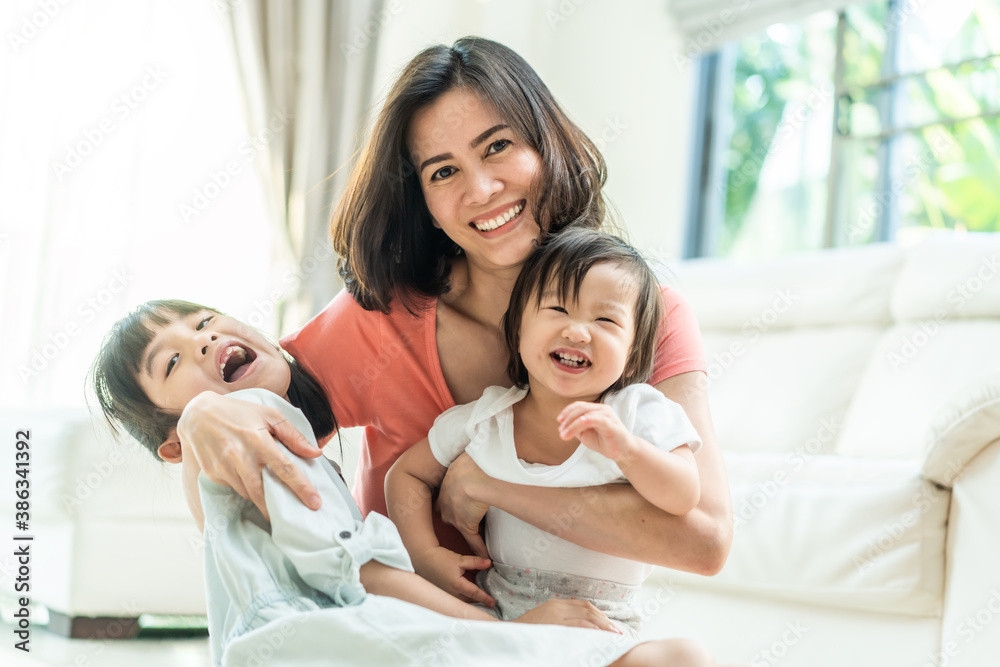 Beautiful mother hugging her children with smiling in the living room.