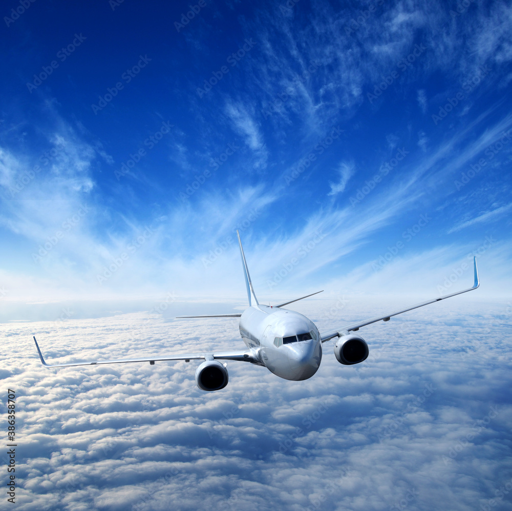 White airplane flying above clouds in the sky