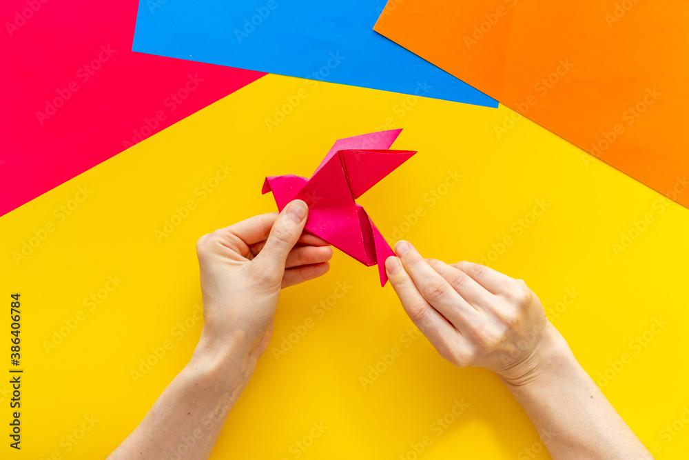 Origami bird in female hands. Care peace concept. Top view