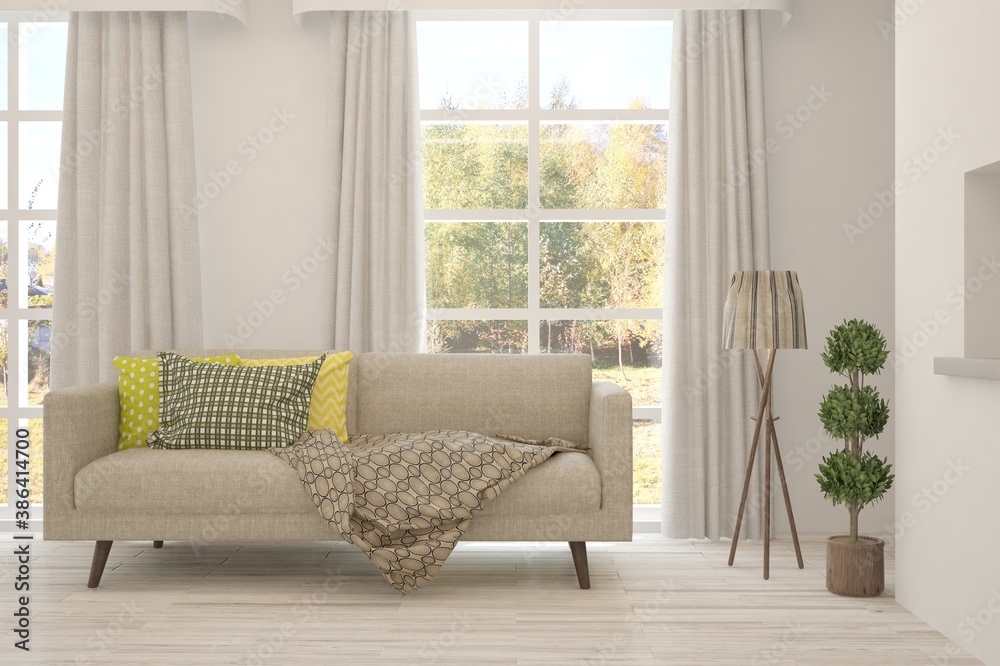 Stylish room in white color with sofa and autumn landscape in window. Scandinavian interior design. 