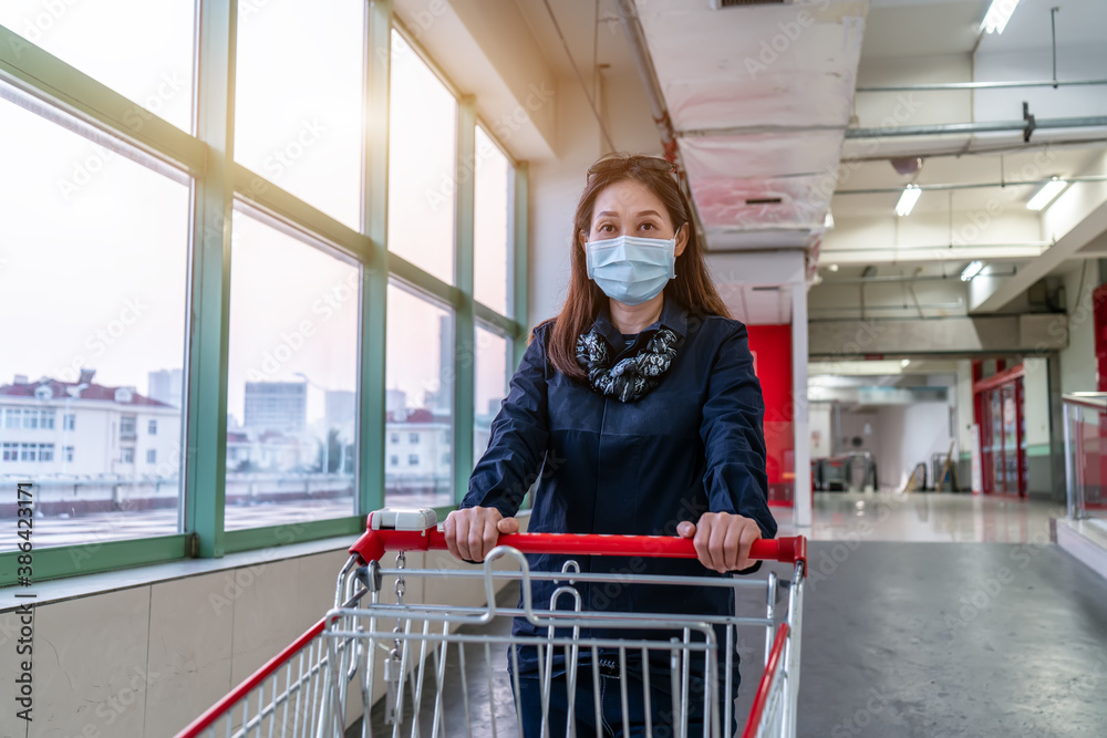 Woman shopping with hand pushing cart in supermarket parking lot