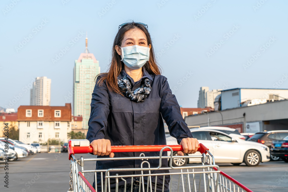 女子在超市停车场推车购物