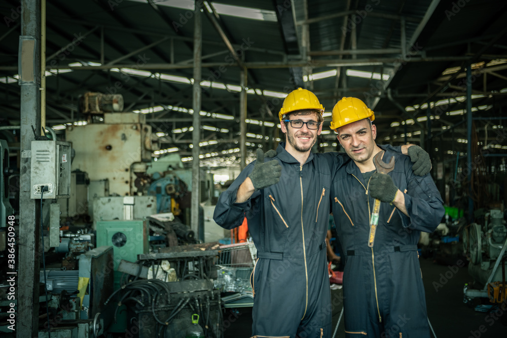 Two male engineers are working on industrial machines. And wear a helmet for safety while working. C