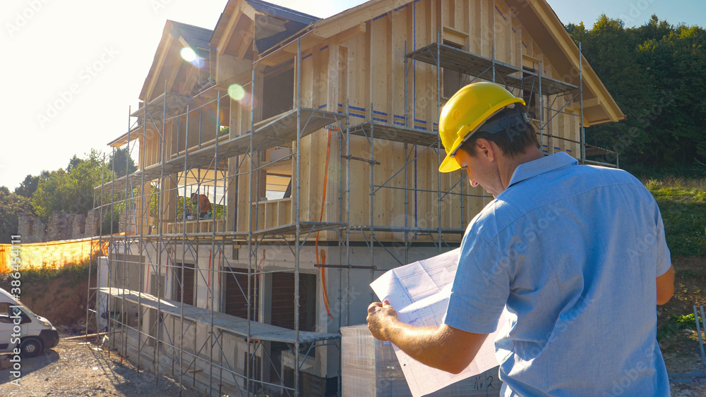 CLOSE UP: Unrecognizable construction site manager looks at the floor plans.