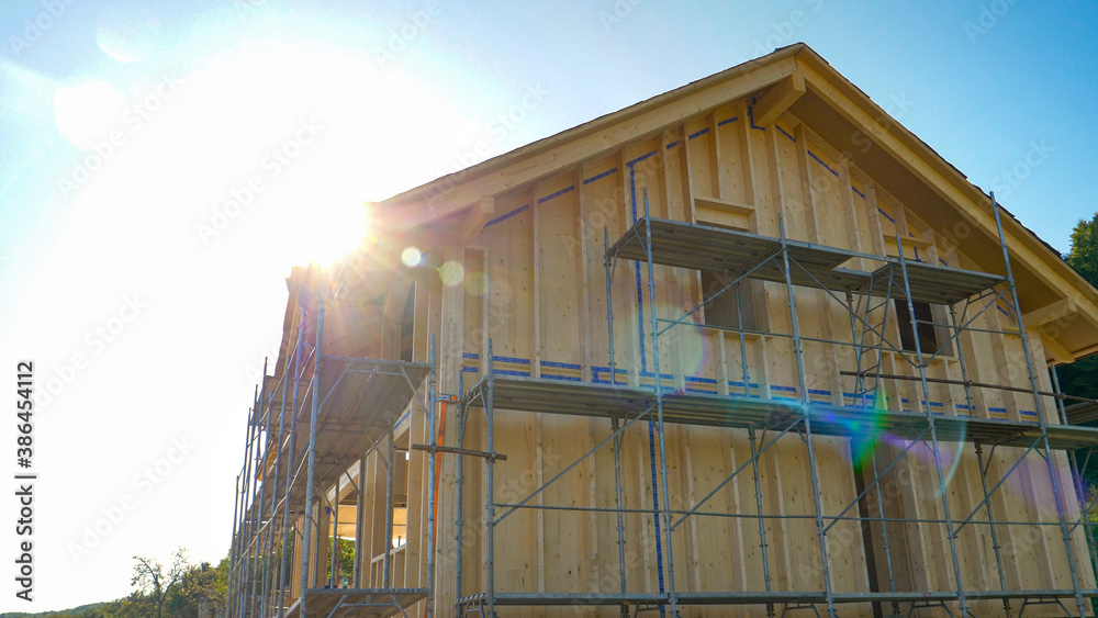 CLOSE UP: Bright sunbeams shine on a wooden house being built in countryside.