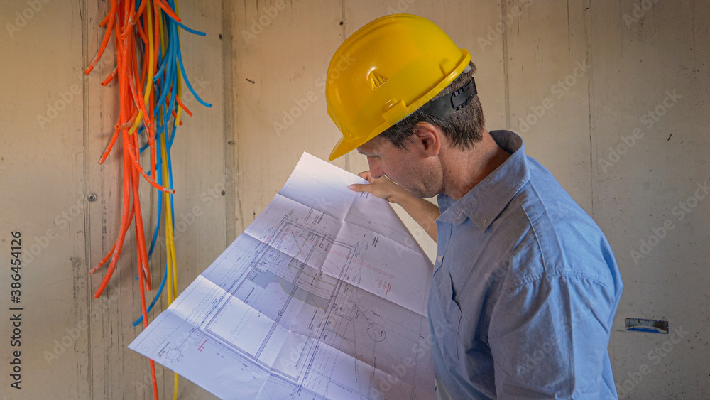 CLOSE UP: Contractor examining installations running through an unfinished house