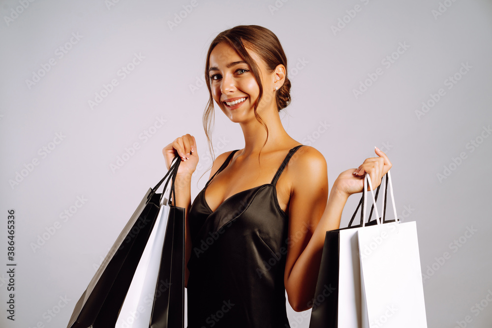 Portrait of beautiful  emotional  young woman posing isolated over grey wall background holding shop