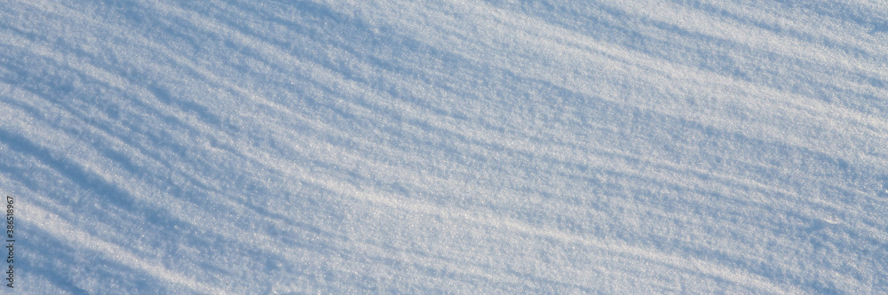 Beautiful winter background with snowy ground. Natural snow texture. Wind sculpted patterns on snow 