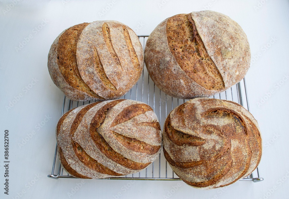 Whole grain homemade rye bread of different shapes on a metal rack