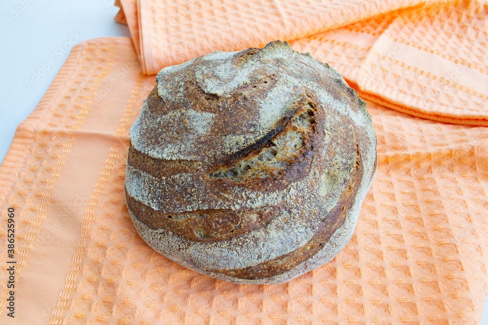 Crispy round rye homemade bread on an orange kitchen towel