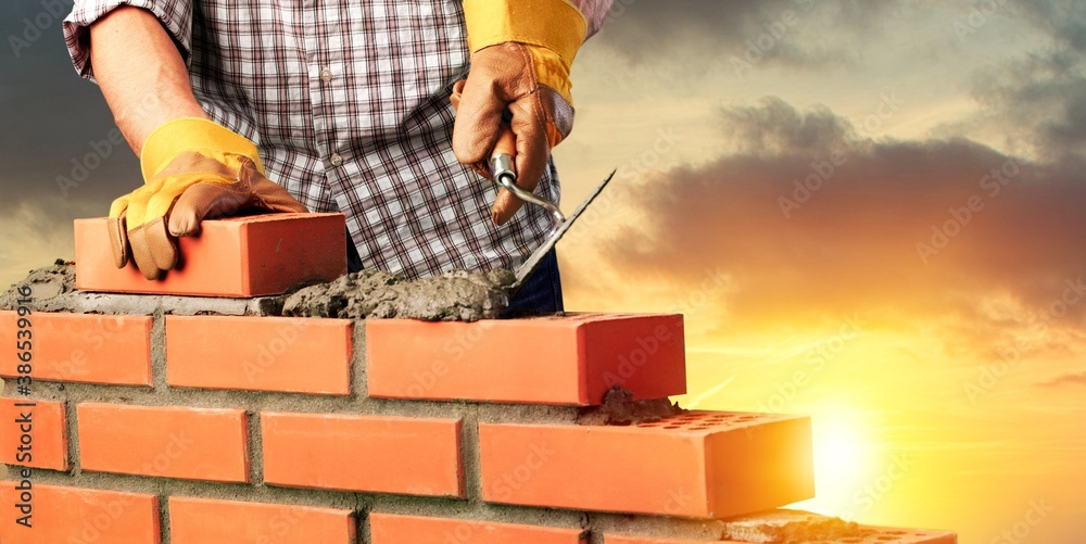 Man worker installing brick masonry wall with a trowel