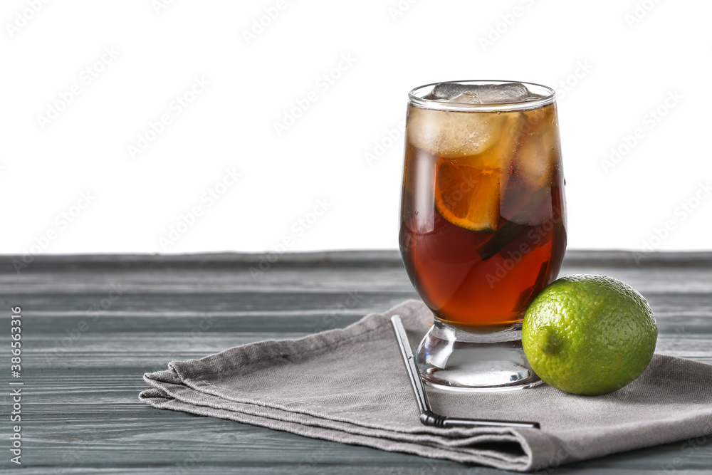 Glass of tasty Cuba Libre cocktail on table against white background