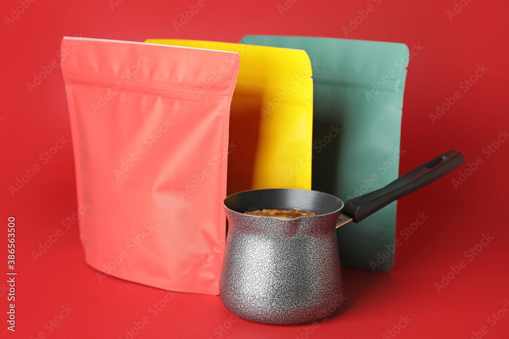 Blank coffee bags and jezve on color background