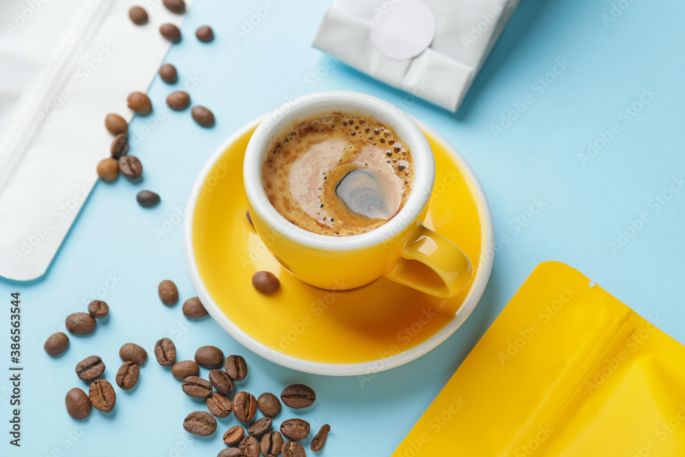 Cup of hot coffee and bags on color background