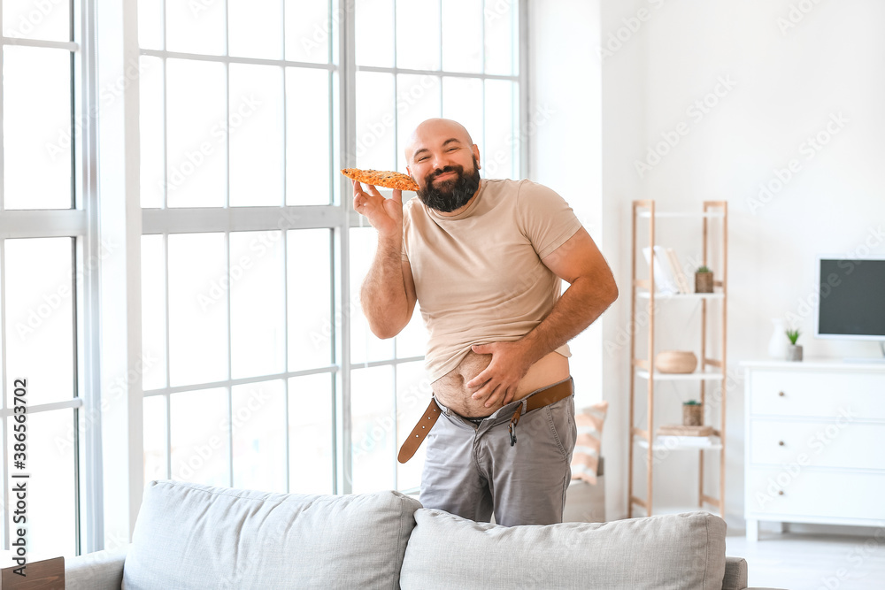 Overweight man eating pizza at home. Weight loss concept