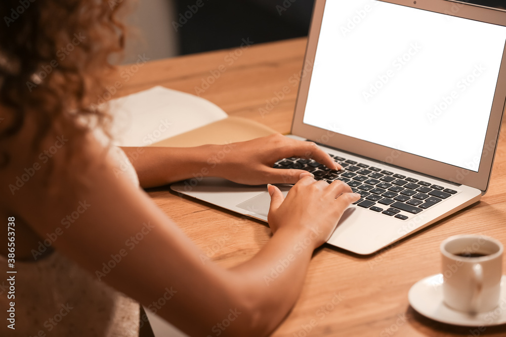 African-American woman working on laptop at home in evening