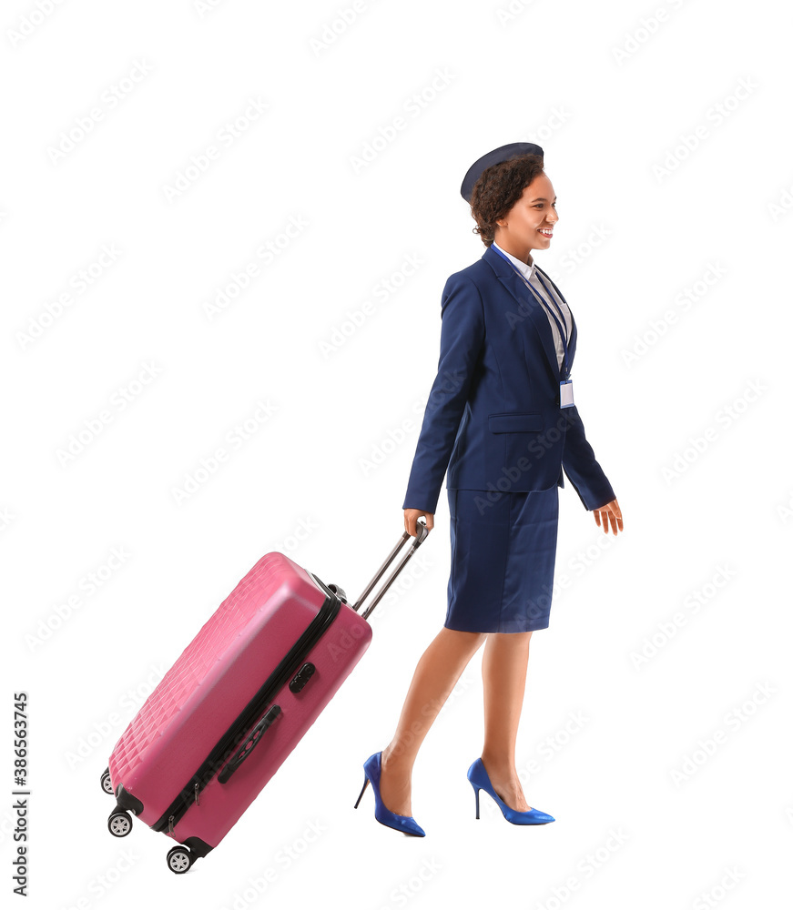 Beautiful African-American stewardess with luggage on white background