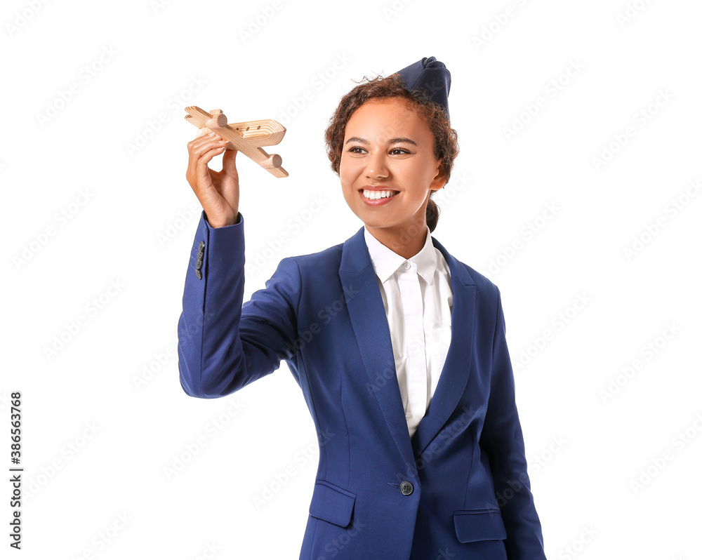 Beautiful African-American stewardess with toy airplane on white background