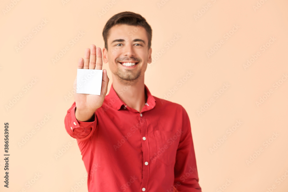 Young man with small blank paper sheet on color background