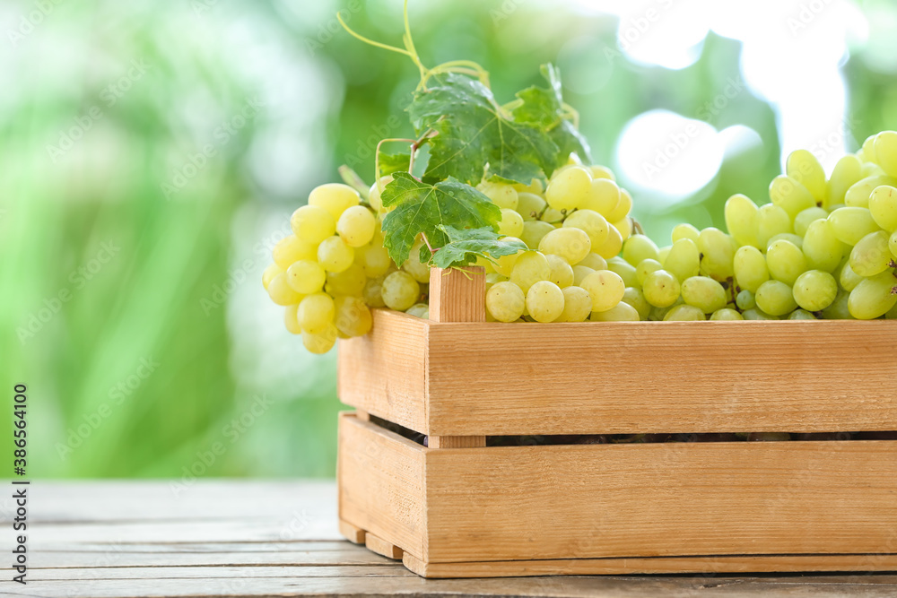 Wooden box with ripe grapes on table outdoors