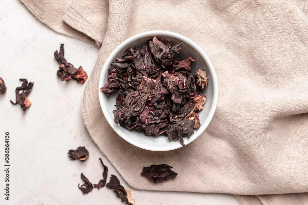 Bowl with dry hibiscus tea on table