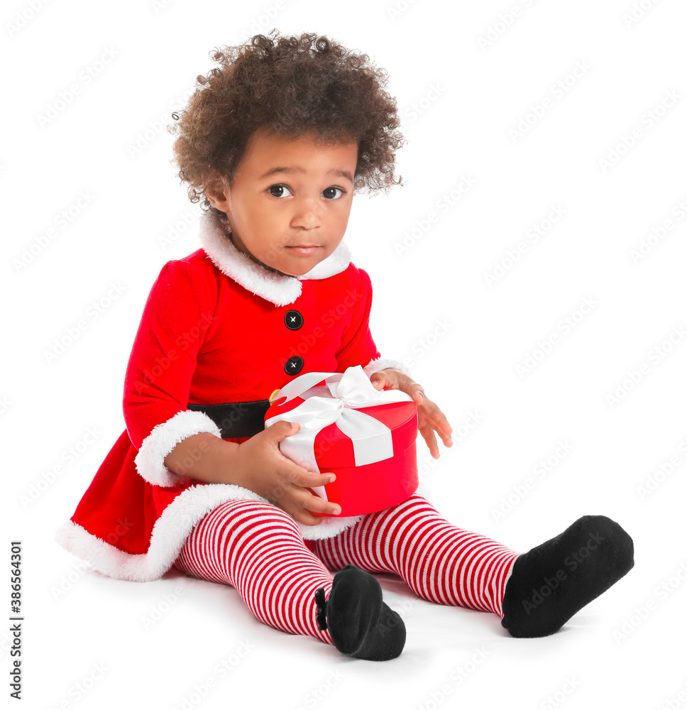 Cute African-American baby girl dressed as Santa and with Christmas gift on white background