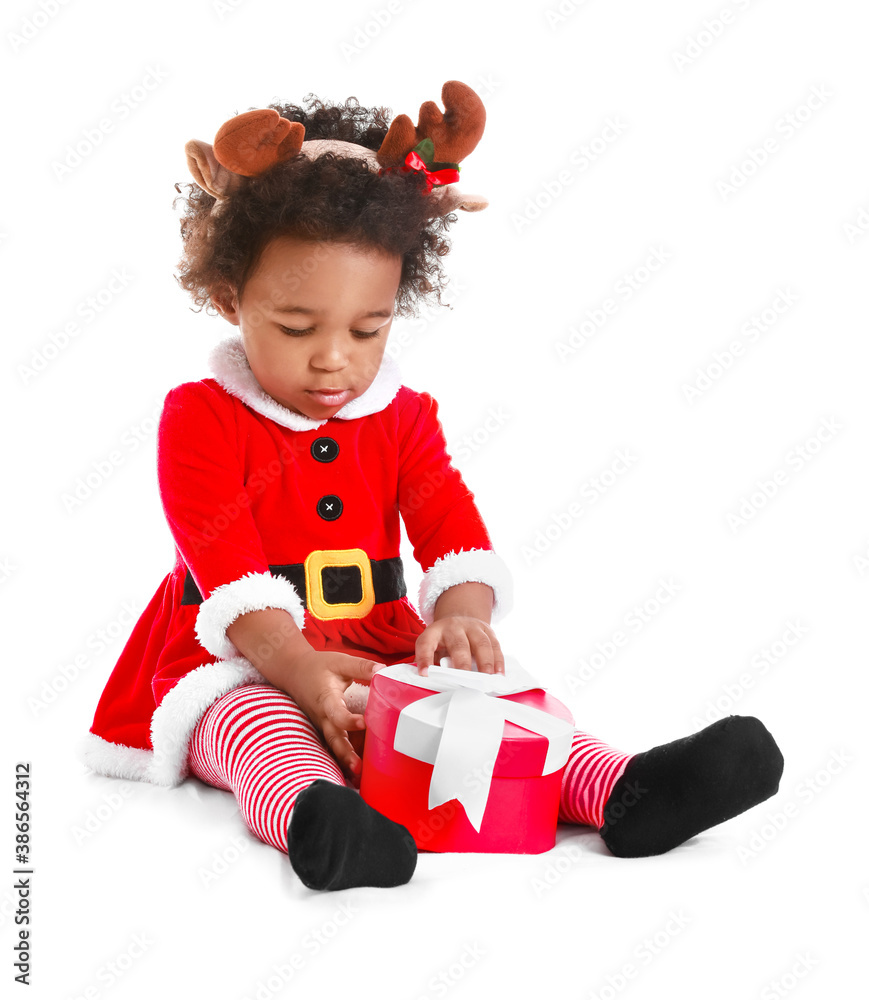 Cute African-American baby girl dressed as Santa and with Christmas gift on white background