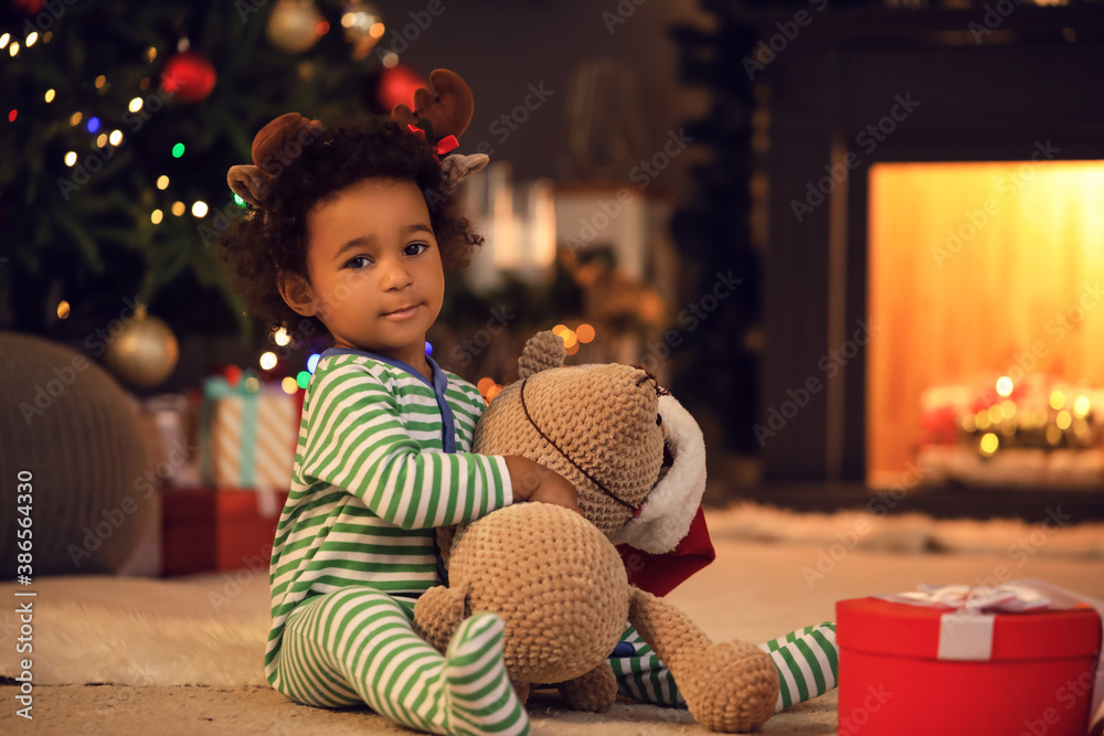 Cute African-American baby girl with toy at home on Christmas eve