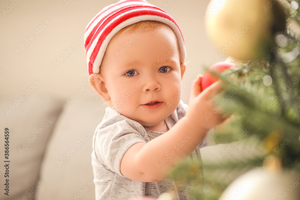 Cute little baby near Christmas tree at home