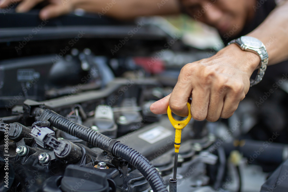 Auto repair center, an auto mechanics hand, is checking the engine oil level so the car is ready to